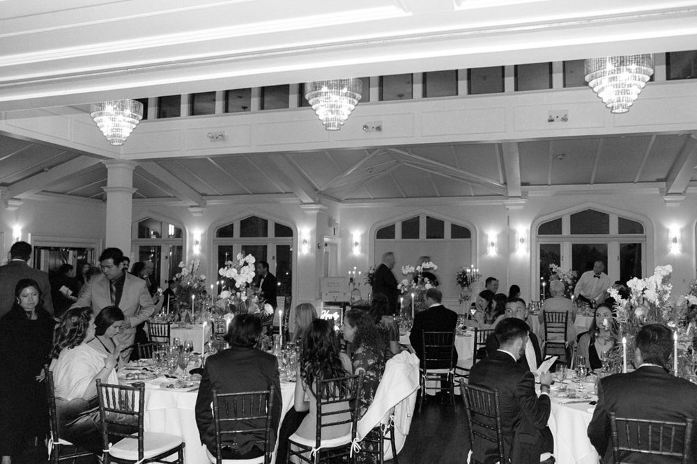 Large wedding reception hall with guests seated at decorated tables.