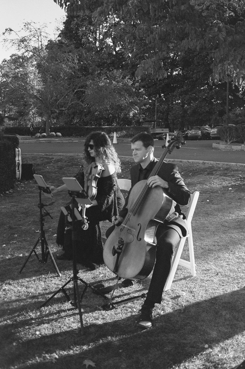 Musicians perform with string instruments at outdoor event during golden hour.
