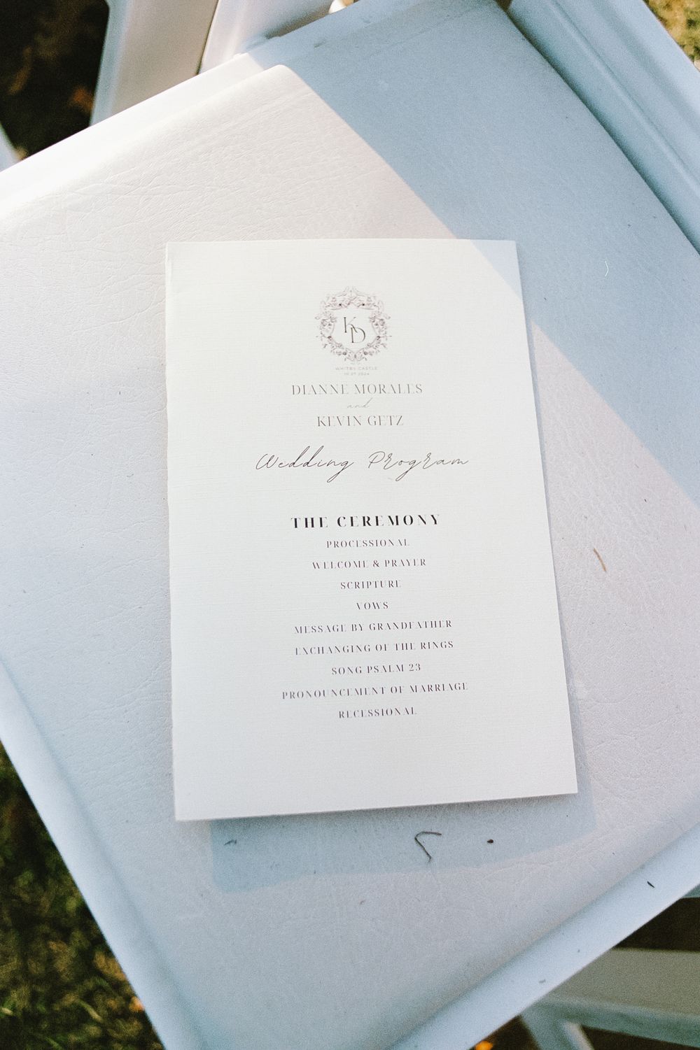 Elegant white wedding invitation with monogram displayed on light blue background.