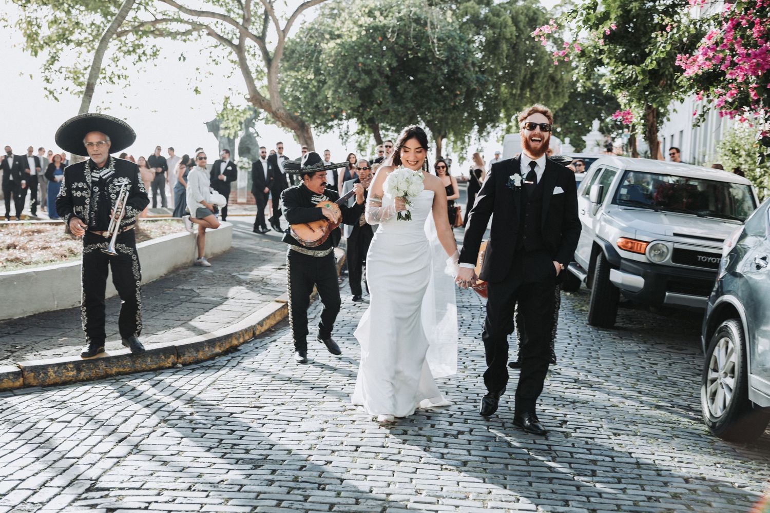 Wedding procession on a cobblestone street with musicians in traditional attire.