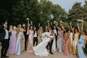 Wedding party in pastel and neutral dresses celebrating outdoors.