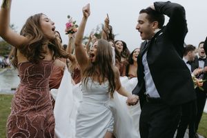Wedding guests dance together joyfully at an outdoor reception celebration.