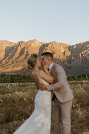 Romantic sunset wedding portrait with desert mountains as backdrop.