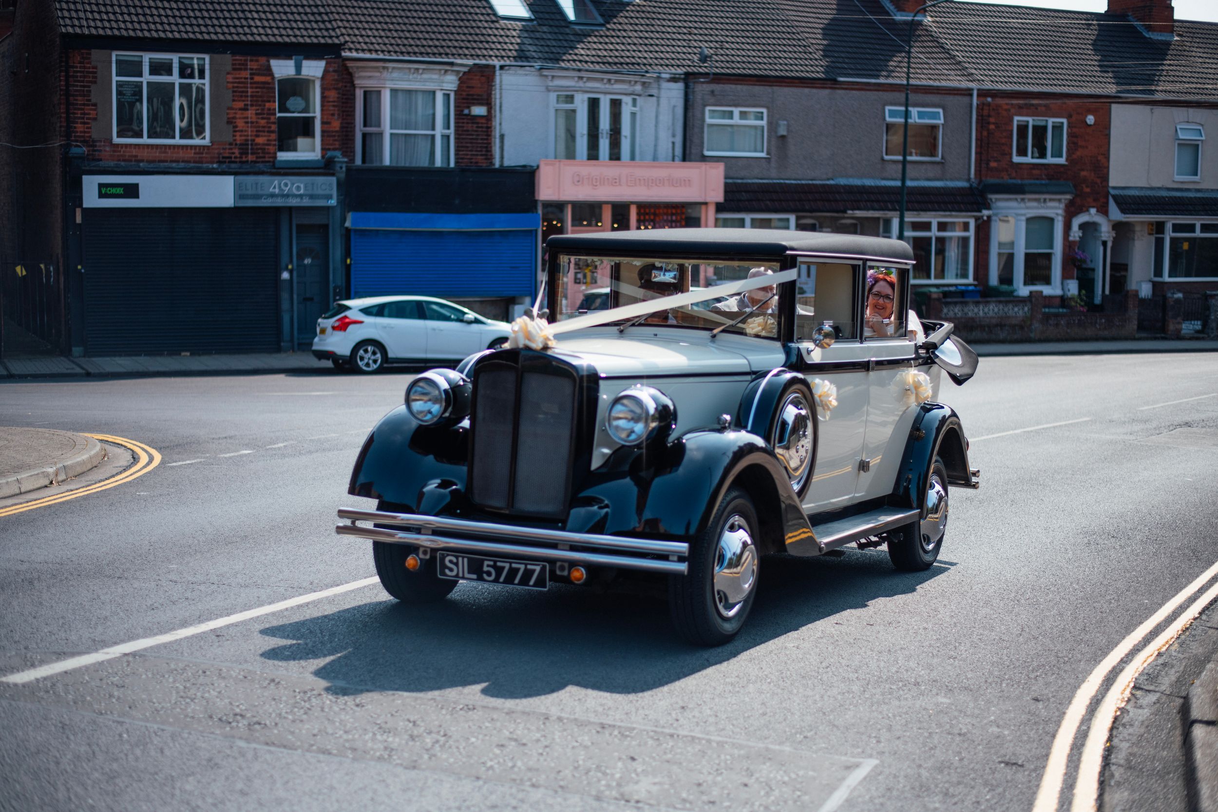 Elegant vintage white wedding car turning on a street corner.