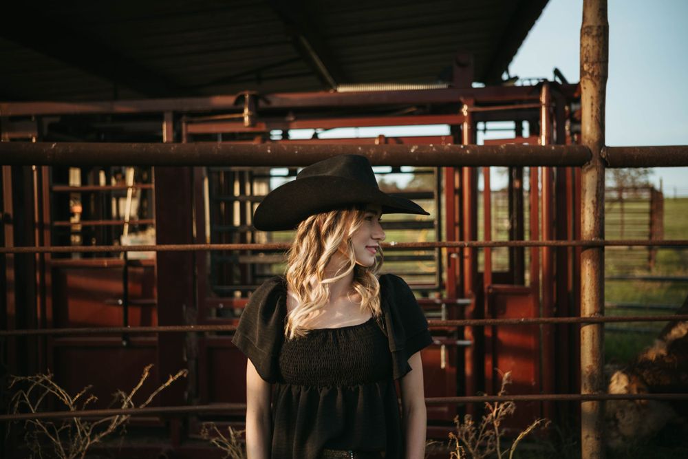 A rustic farm scene with corral gates and fence posts at sunset.