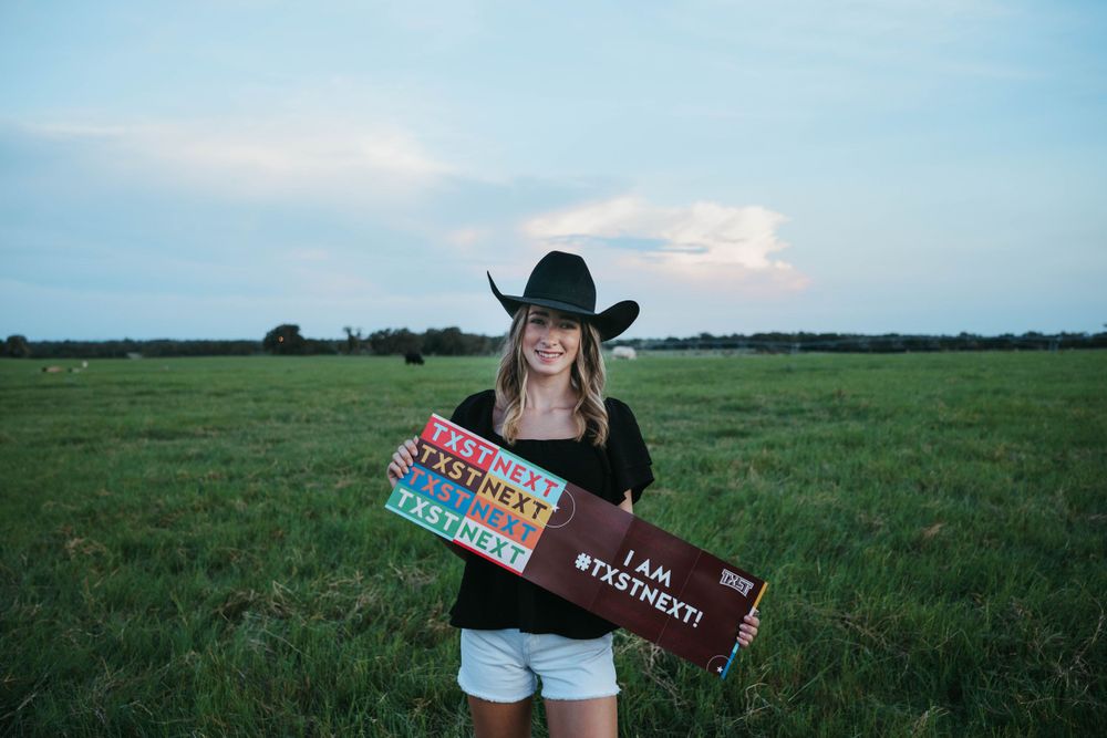 Cowboy hat and vintage-style signs held in open field at sunset.