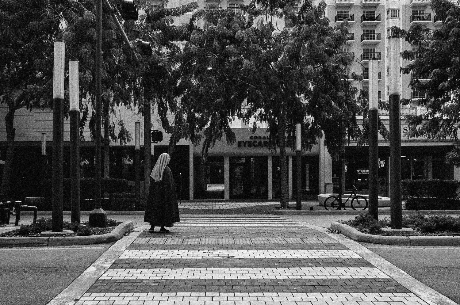 Pedestrian crossing a brick paved crosswalk on an urban street in black and white.