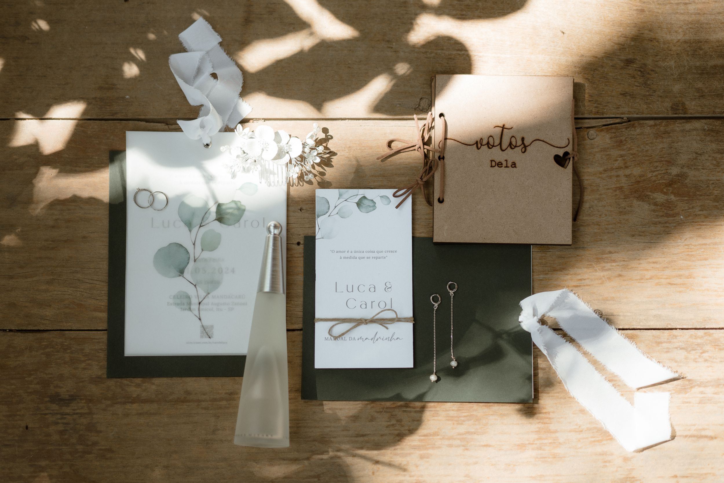 Wedding stationery and invitation suite arranged on wooden surface in dappled sunlight.