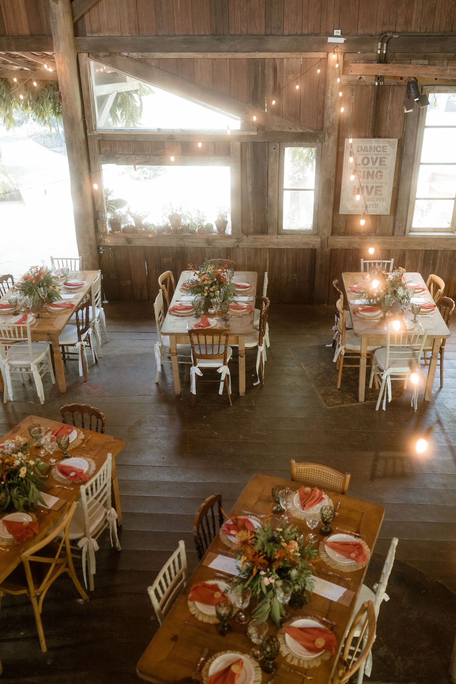 Rustic barn reception venue with wooden tables and string lights creating a warm atmosphere.