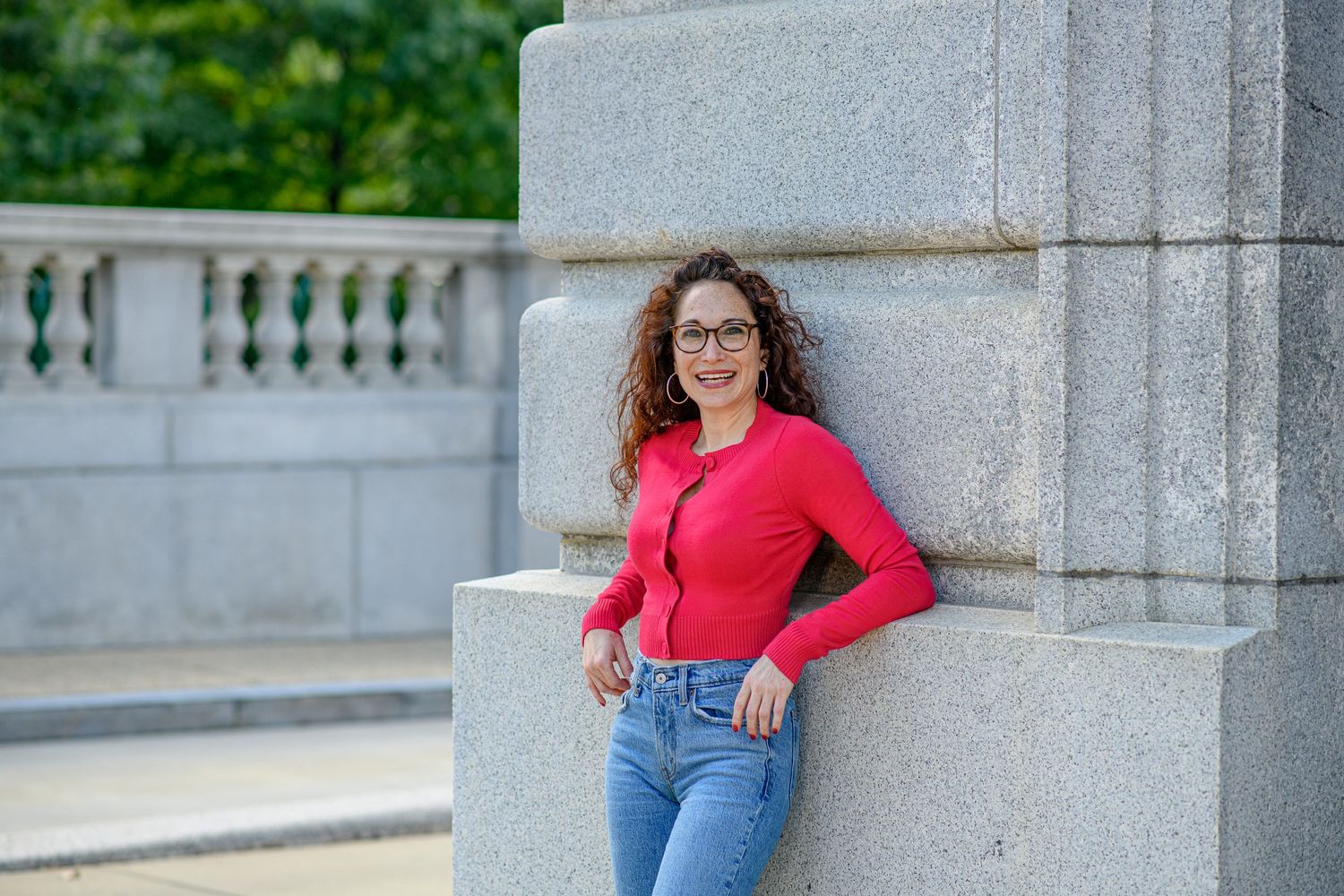 Portrait at a stone monument featuring a casual pose against classic architecture.