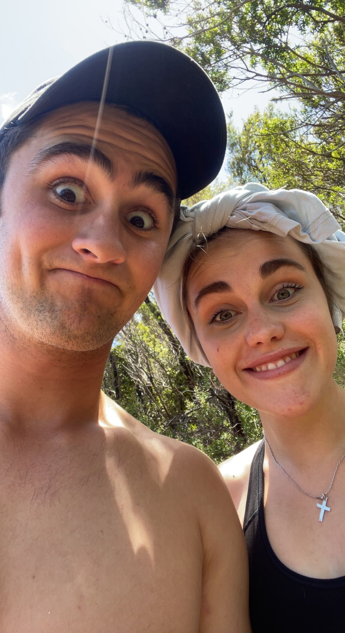 Casual selfie of two people outdoors wearing baseball cap and headband.