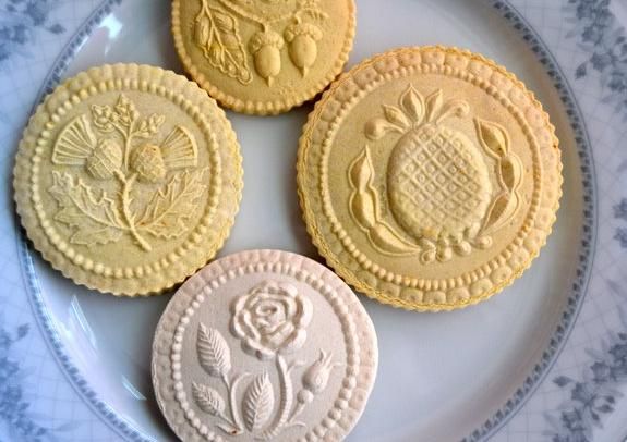 Traditional stamped butter cookies with decorative rose and floral patterns arranged on a light blue surface.
