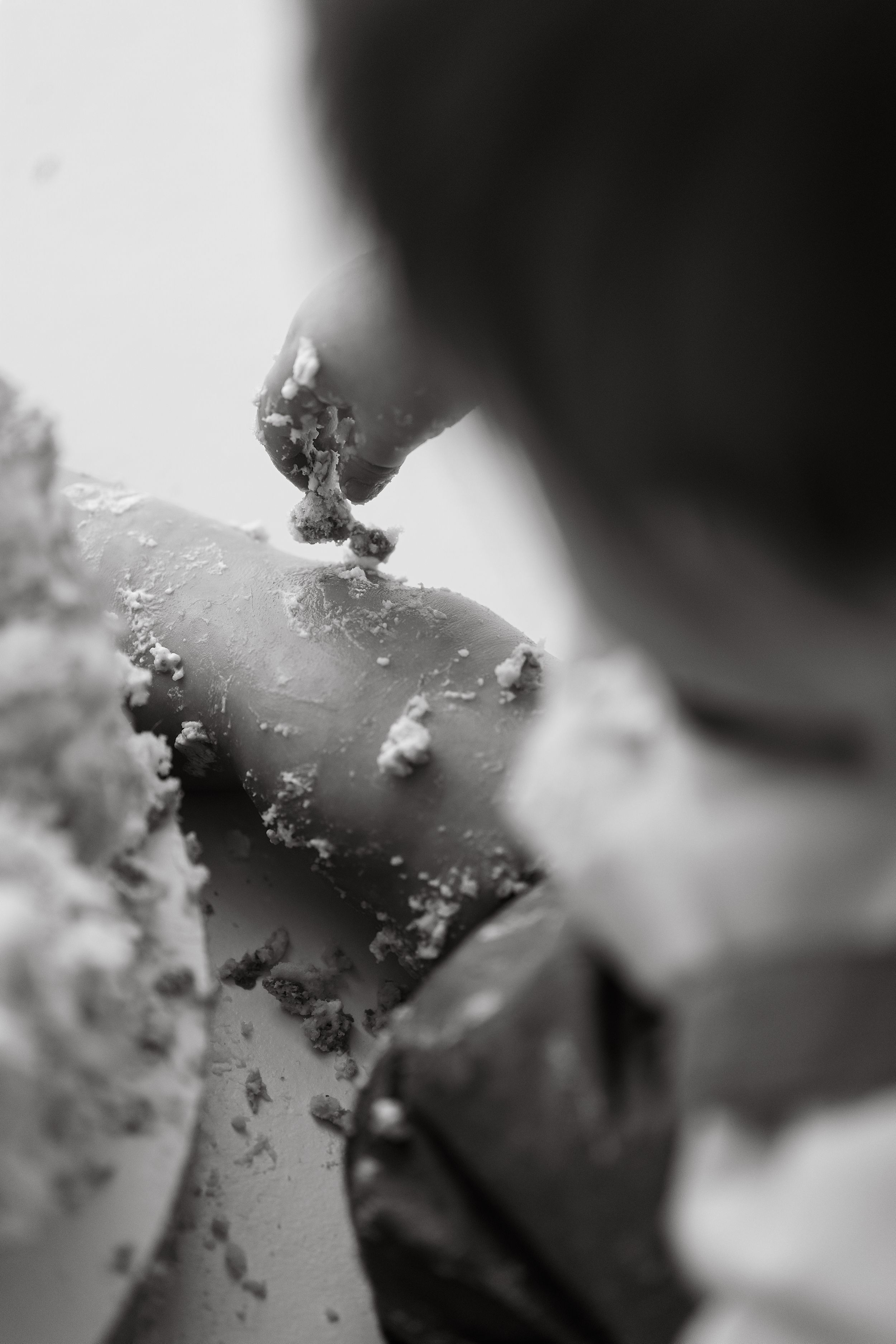 Black and white close-up of a baby smashing a birthday cake with frosting-covered fingers.