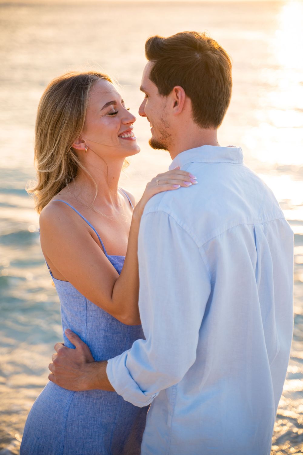 A couple shares a romantic moment on the beach at sunset.