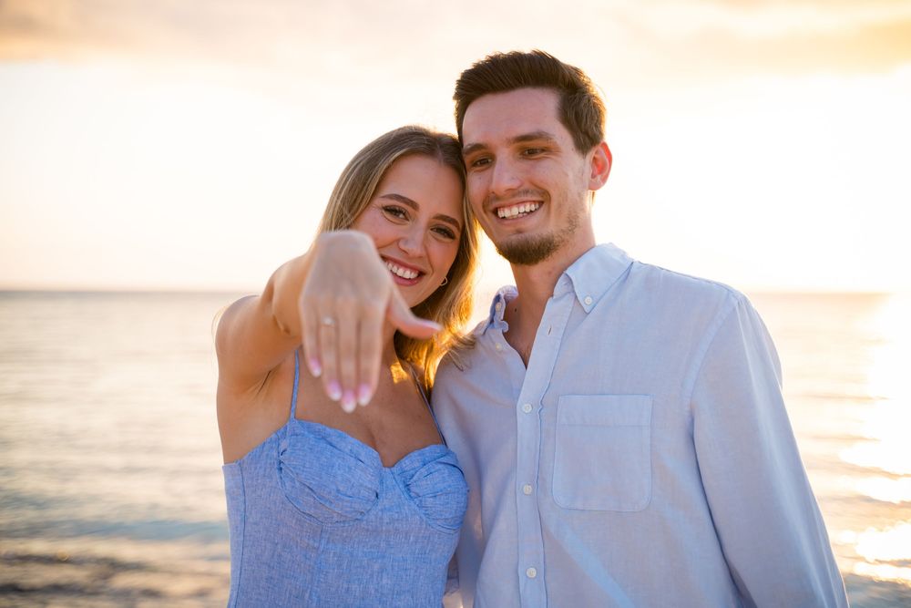 A couple laughs together during their beach photoshoot at golden hour.