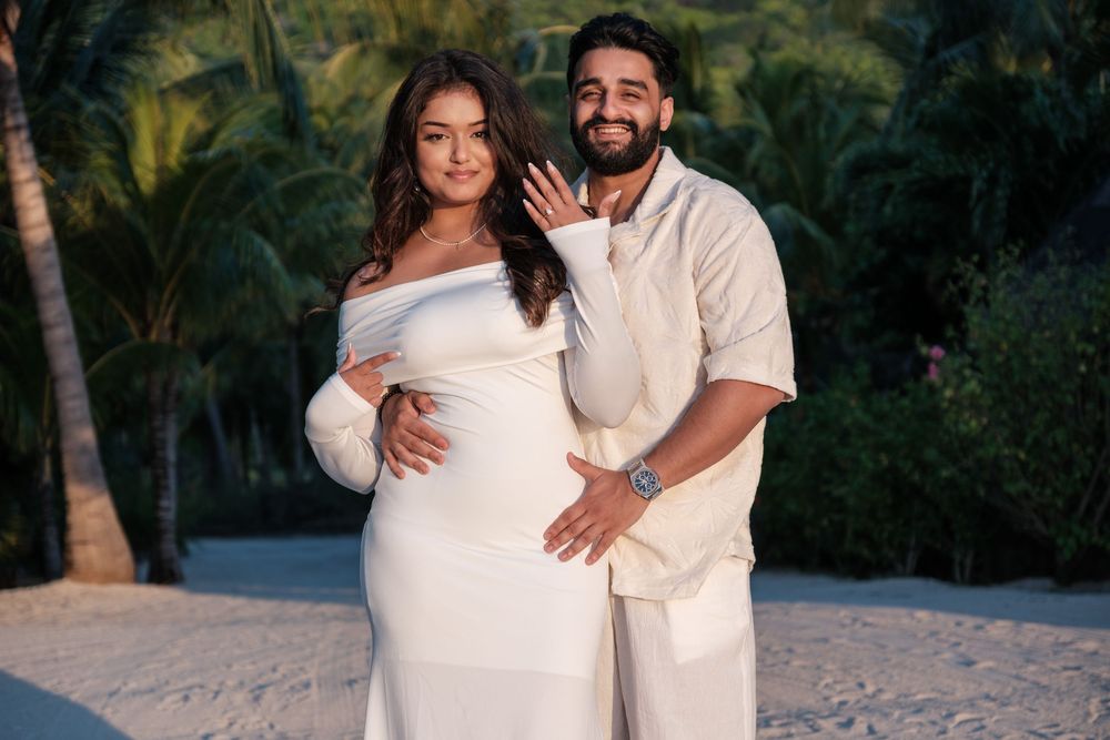 A couple embraces on a tropical beach path surrounded by palm trees.