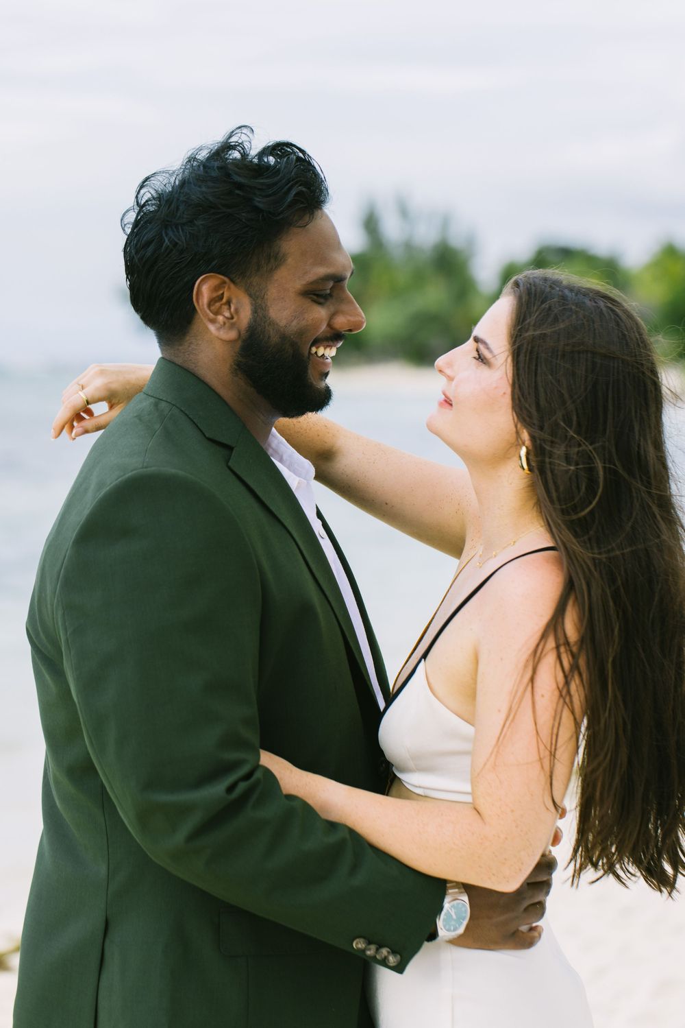 Happy couple embracing outdoors with scenic water and mountain view.