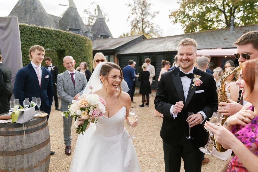 Wedding guests mingle and celebrate at an outdoor reception venue with wine barrels and rustic decor.