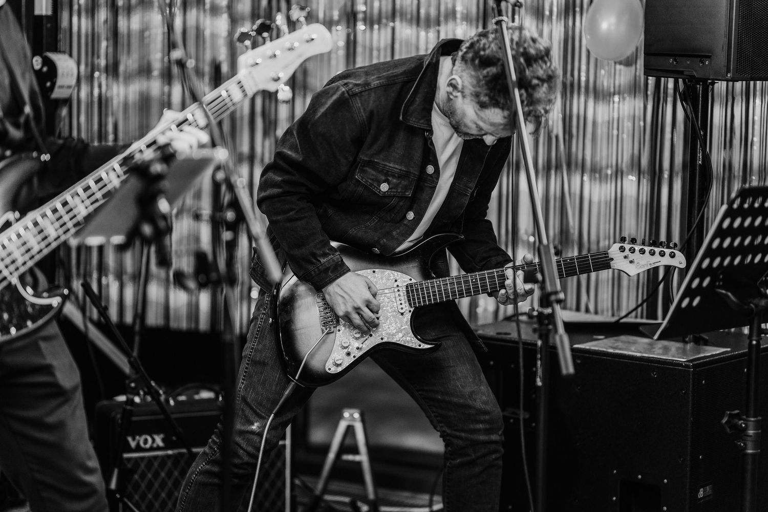 Detailný umelecký záber gitaristu na pódiu, zachytenie energie a atmosféry hudobného podujatia, event fotograf.