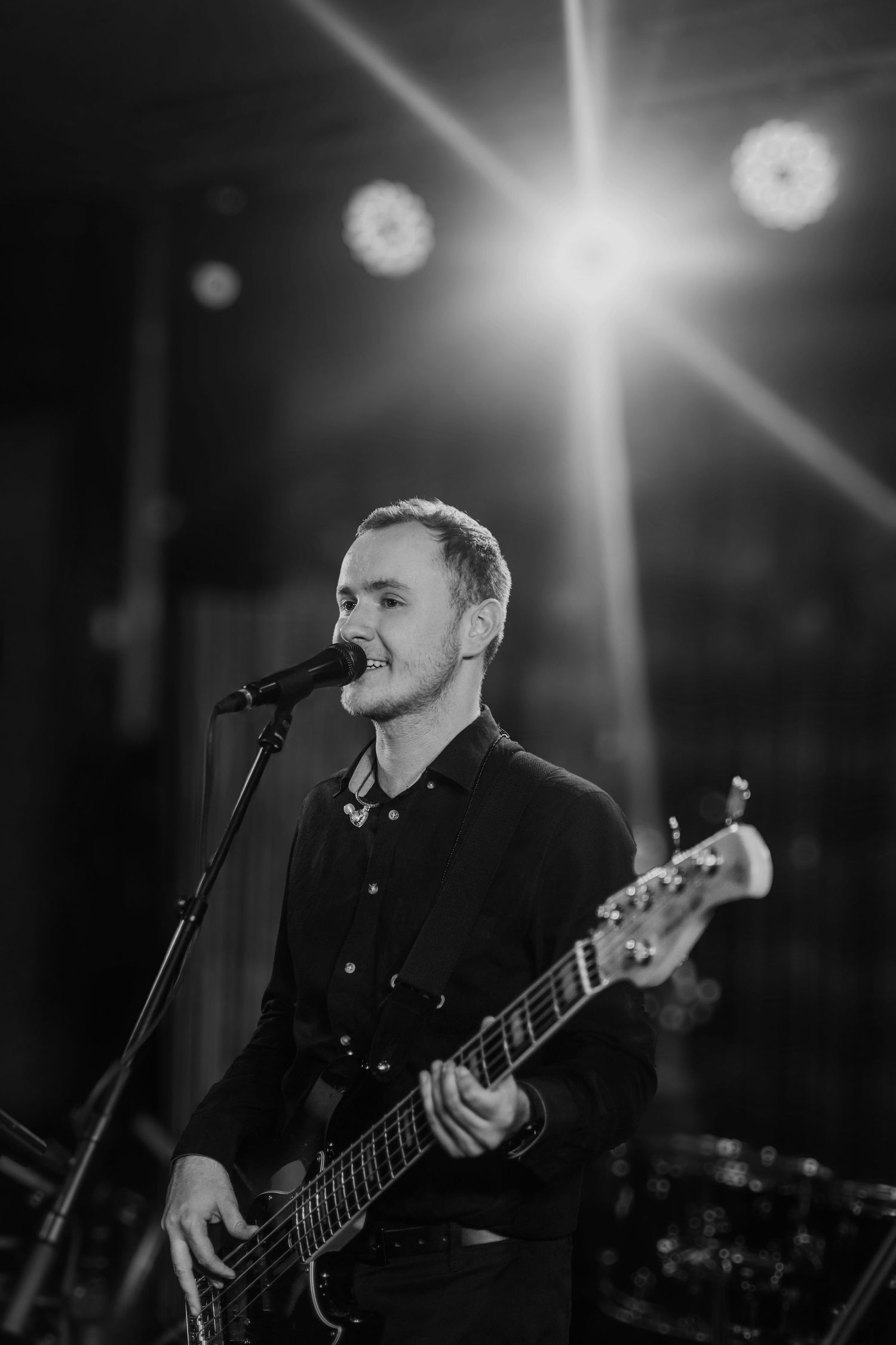 Zachytenie energie na pódiu, basgitarista počas koncertu pod reflektormi, profesionálna eventová fotografia.
