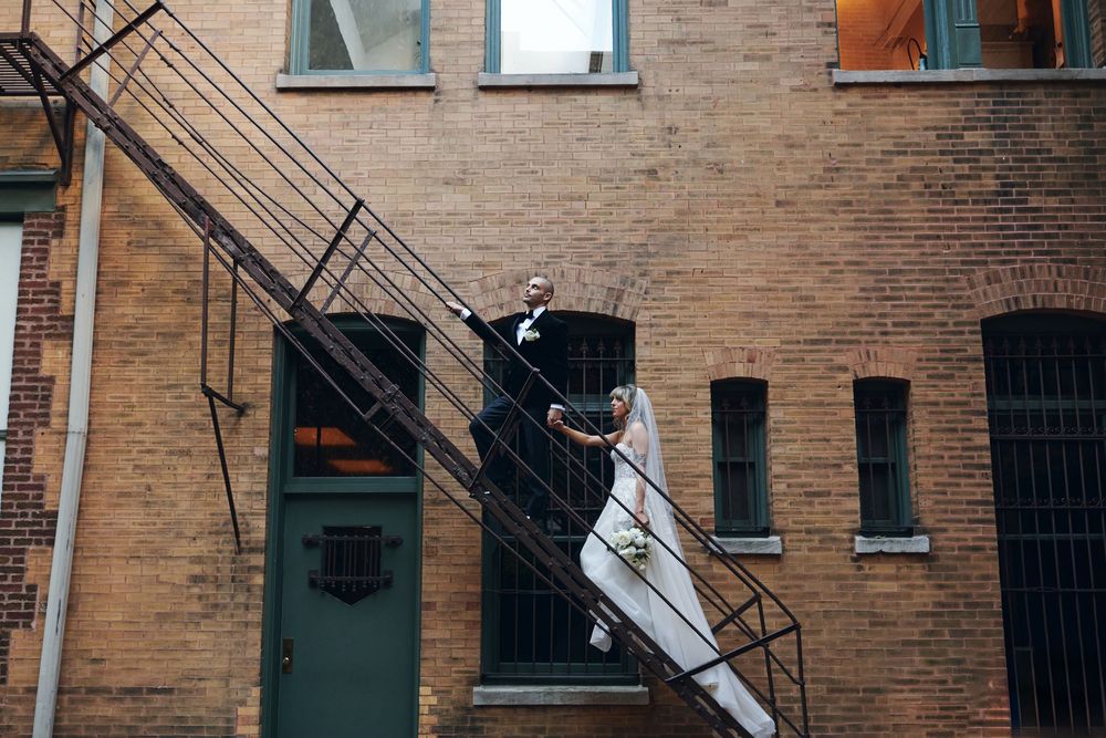 Brick apartment building with metal fire escapes and barred windows on a city street.