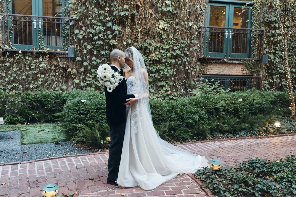 A sequence of romantic wedding moments captured on a brick pathway surrounded by greenery and urban architecture.