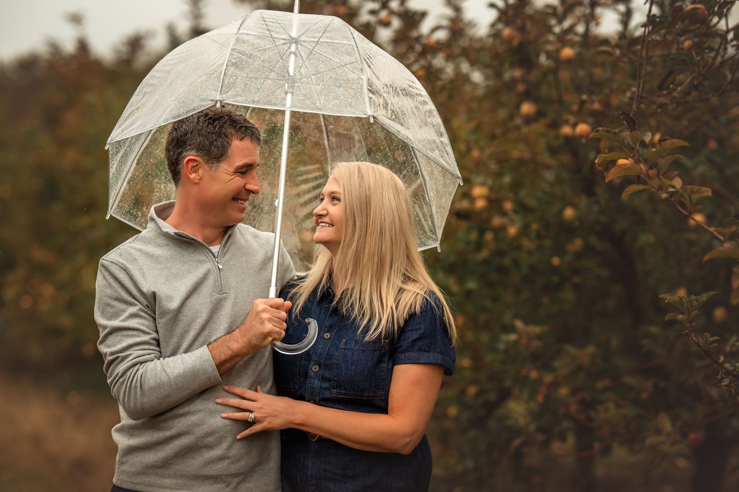 Couple sharing romantic moments outdoors during autumn with warm fall foliage in the background.