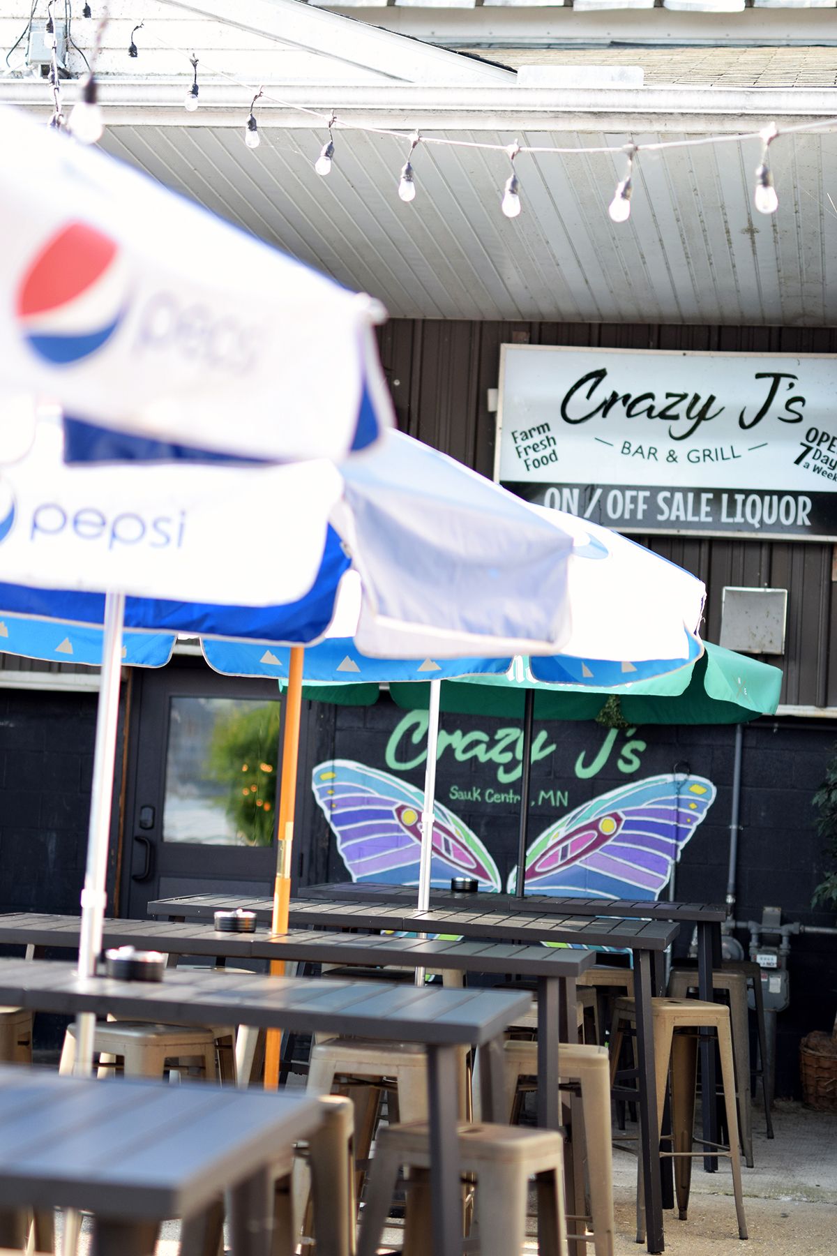 Outdoor restaurant patio with blue Pepsi umbrellas and 'Crazy J's' signage visible.