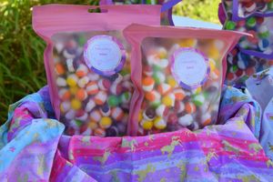 Pink and purple candy bags filled with colorful sweets arranged in rows.
