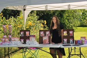Outdoor event setup with white tent and decorative displays in a sunny garden setting.