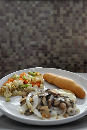 Submarine sandwich with mushrooms, coleslaw and toppings on white plate.