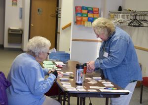 People seated at tables in a community room working on activities.