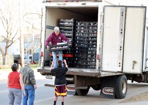 Delivery trucks parked outside a building with people unloading supplies.
