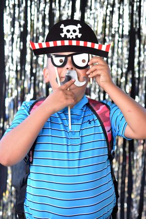 Person in striped shirt posing with various pirate-themed photo booth props.