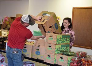 Volunteers work together to distribute items across multiple tables in a community service setting.