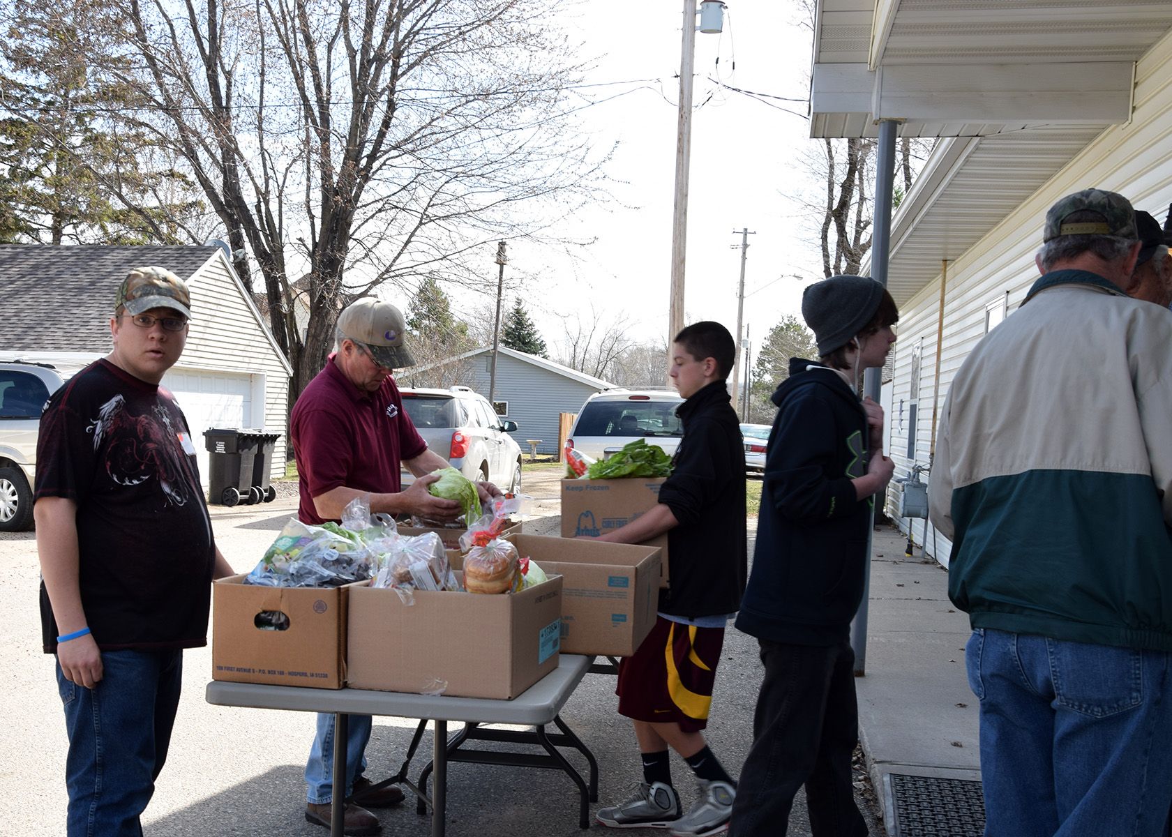 Volunteers distribute items from tables set up outside a building on a winter day.
