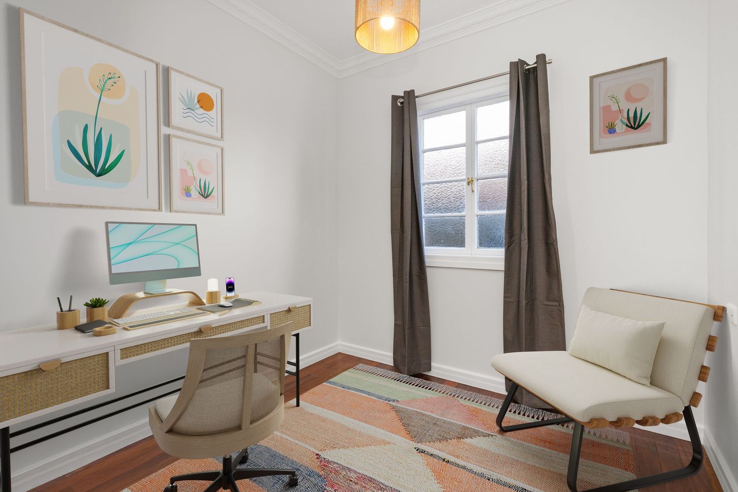Home office with white desk, computer, lounge chair, patterned rug, and decorative wall art.
