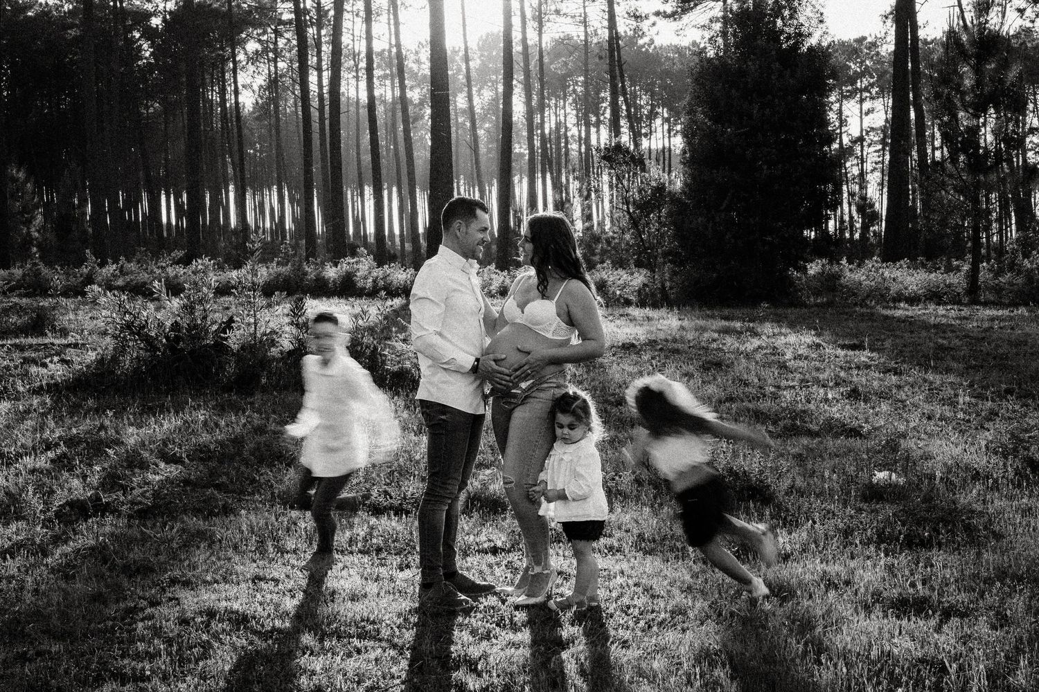 A series of black and white photographs showing people playing and running through a wooded area in vintage clothing.