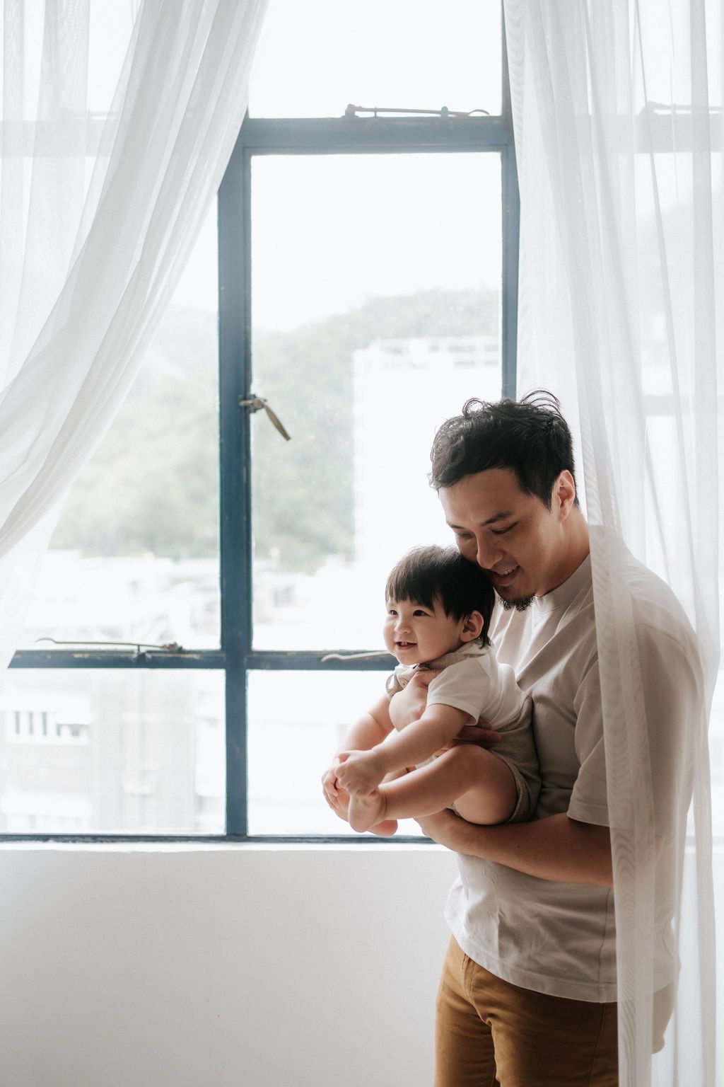 Family sits together on a white couch with pampas grass decor in a cozy minimalist setting.一家人圍坐在白色沙發上，周圍環繞著蘆葦草裝飾，營造出溫馨簡約的氛圍。