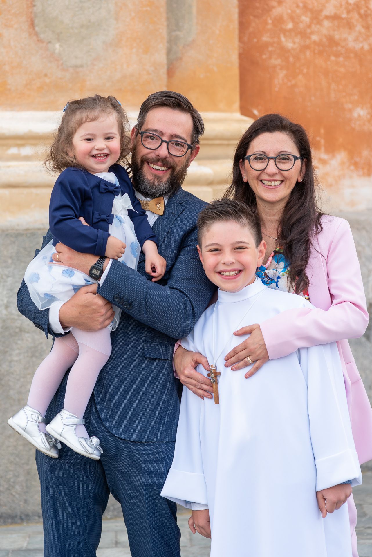 Happy family gathered outside church for religious celebration wearing formal attire.