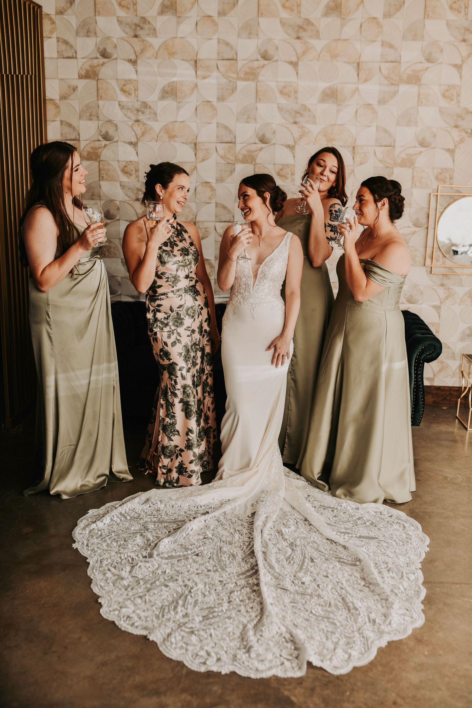 Bride and bridesmaids raising champagne glasses together during joyful bridal suite wedding morning celebration.
