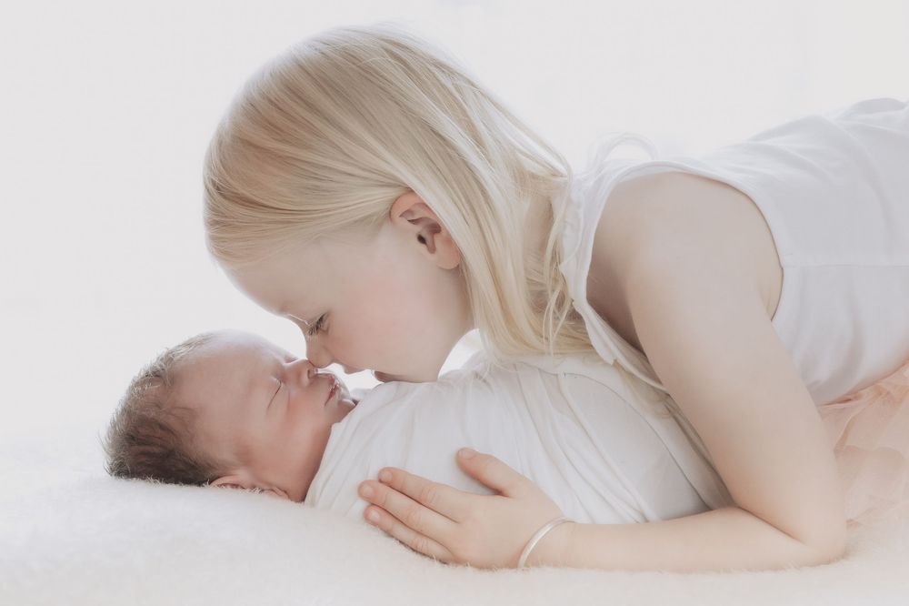 A baby lies sleeping peacefully on soft white bedding in a series of connected images.