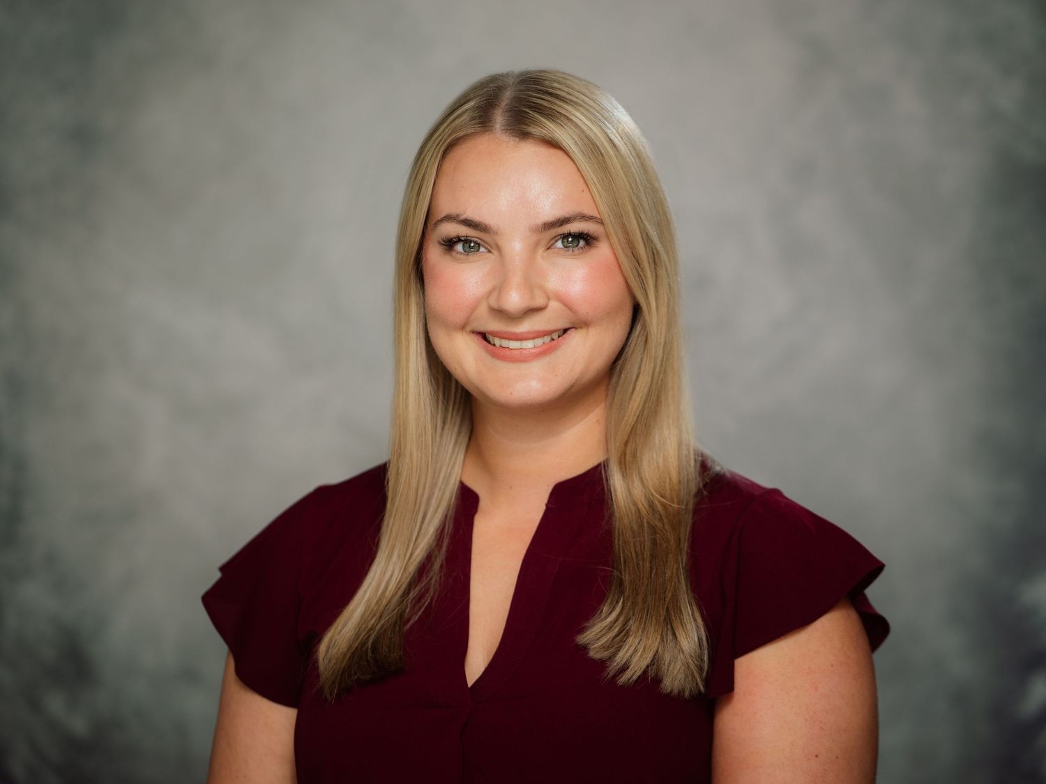 Professional headshot portraits of a blonde woman in a burgundy top against a textured gray backdrop.