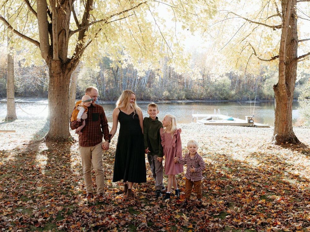 Family portrait session in a scenic autumn setting with trees and fallen leaves. Fall lakeside family photos at lake Michigan.