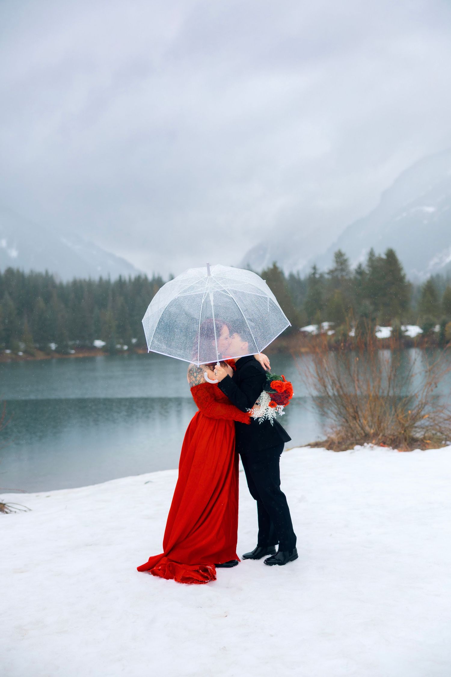 A person's hand reaches out to catch falling snowflakes against a blurred winter forest background.