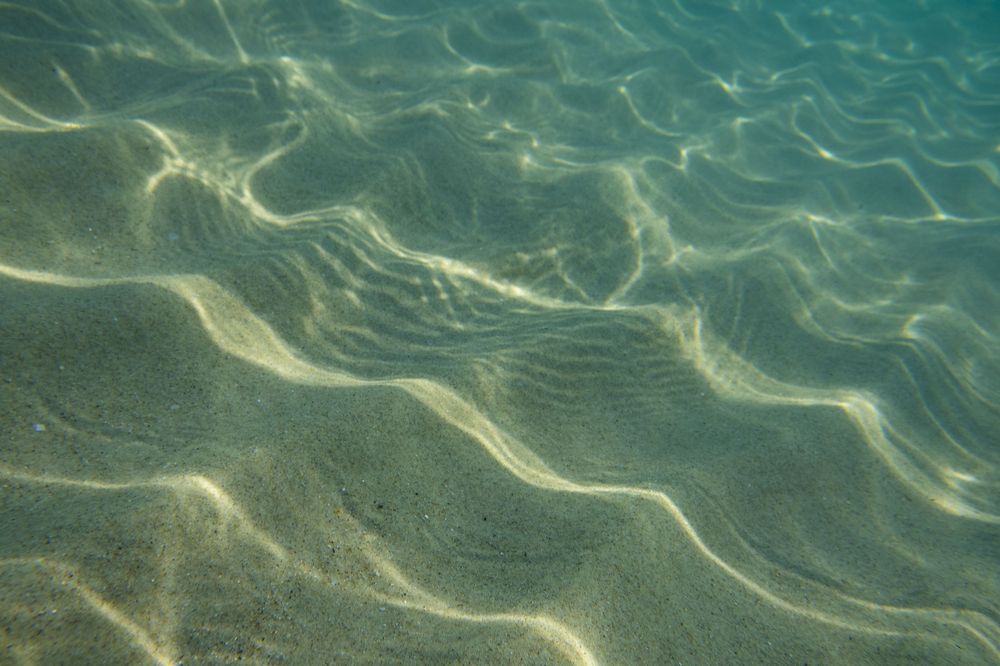 Rippling turquoise water creates mesmerizing patterns of sunlight and shadows on the ocean surface.