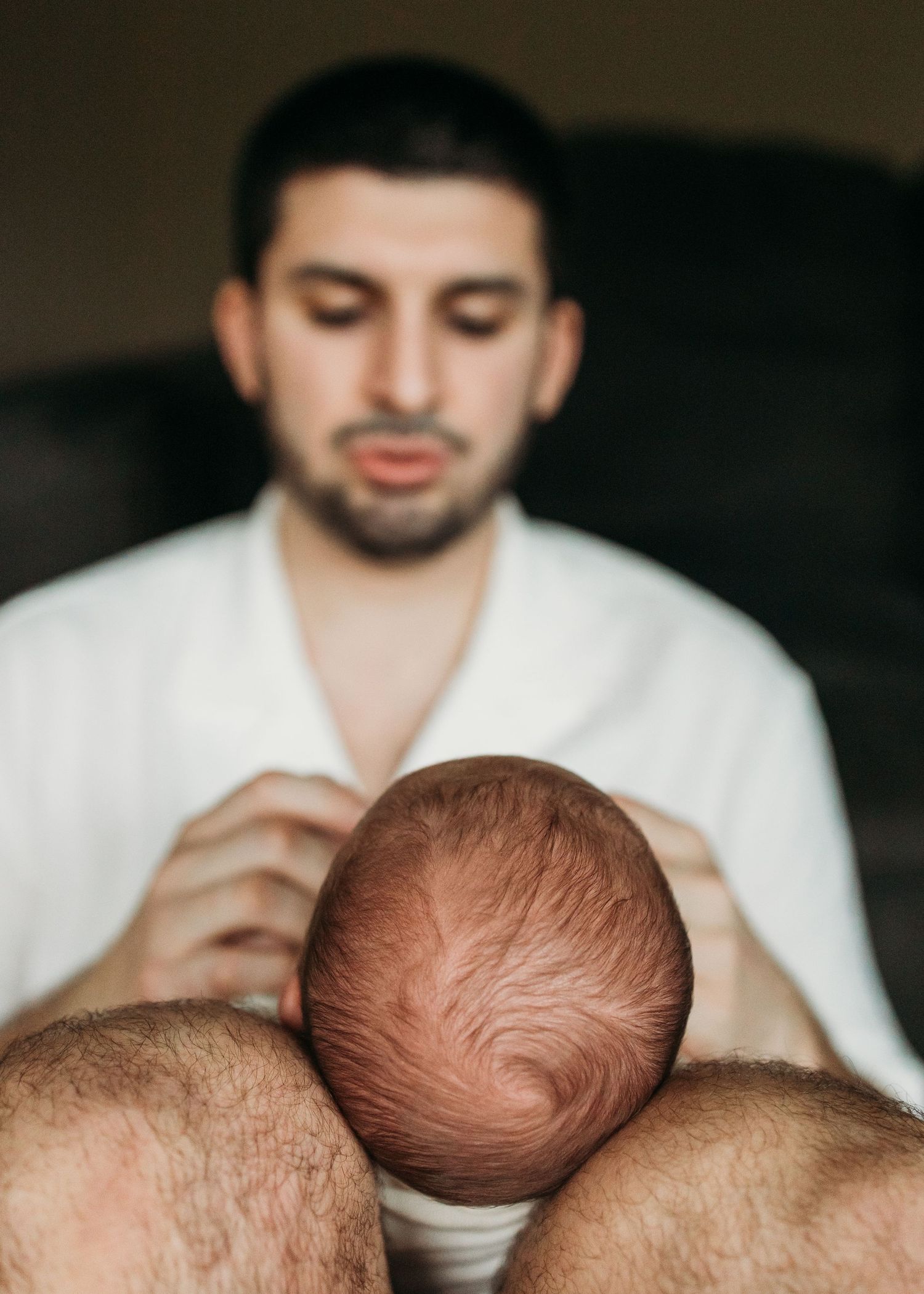 A series of close-up photos showing a baby's head with dark hair being gently touched by hands in white sleeves.