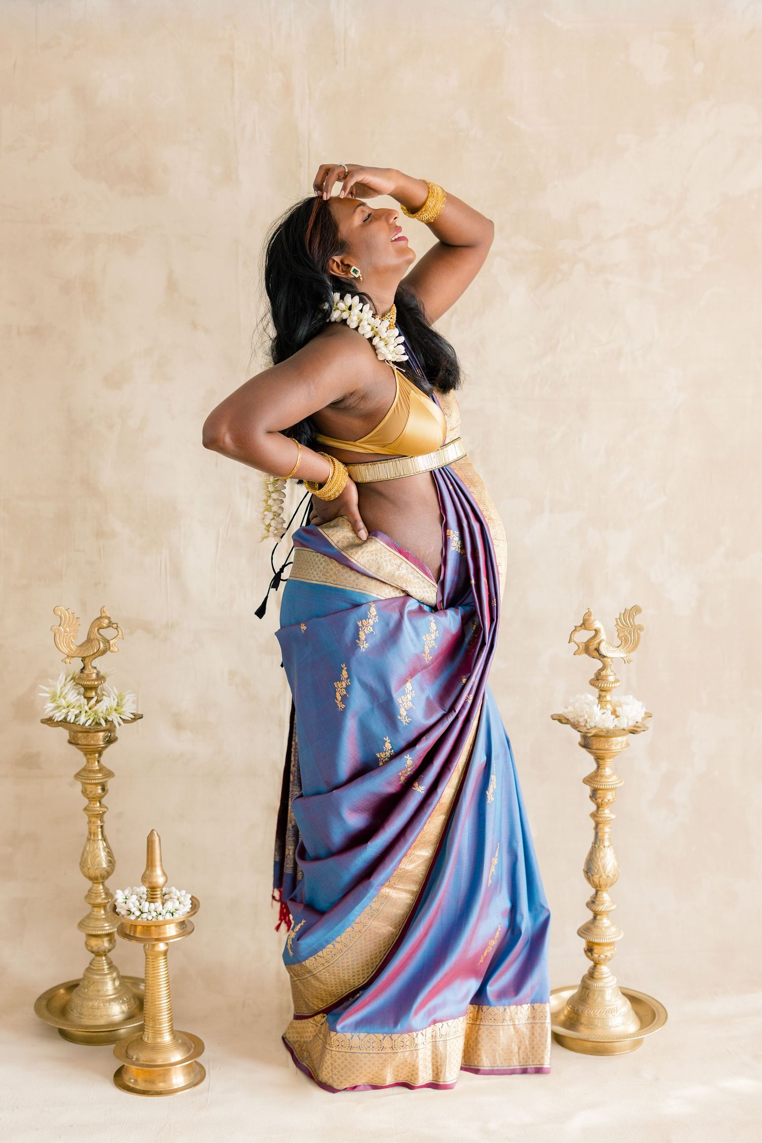 A series of artistic photos showing a person in a blue and gold sari posing gracefully with brass candlesticks.