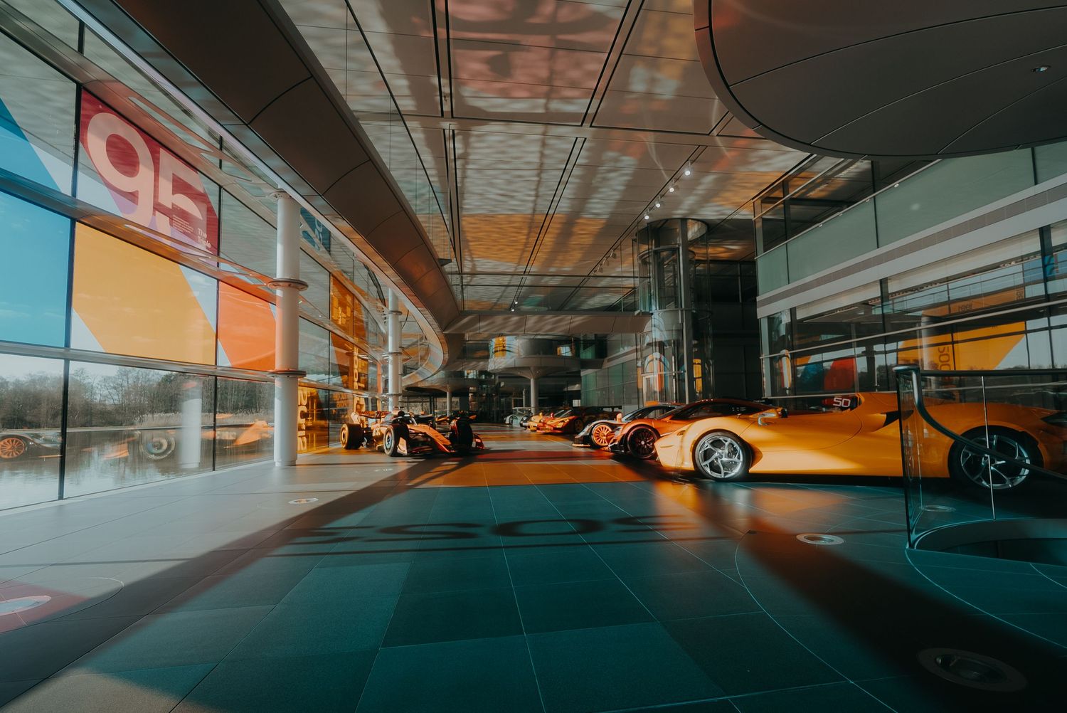 Modern underground parking garage with orange lighting and luxury cars parked in diagonal spaces.
