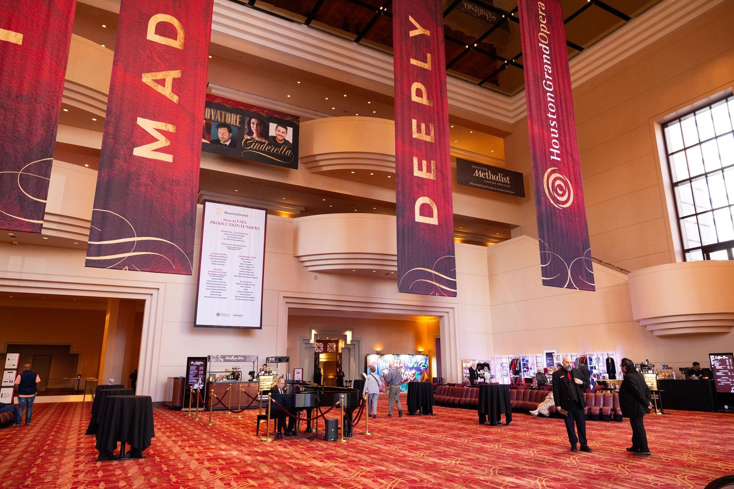 A panoramic view of a large convention center hall with banners, booths and attendees spread across the space.